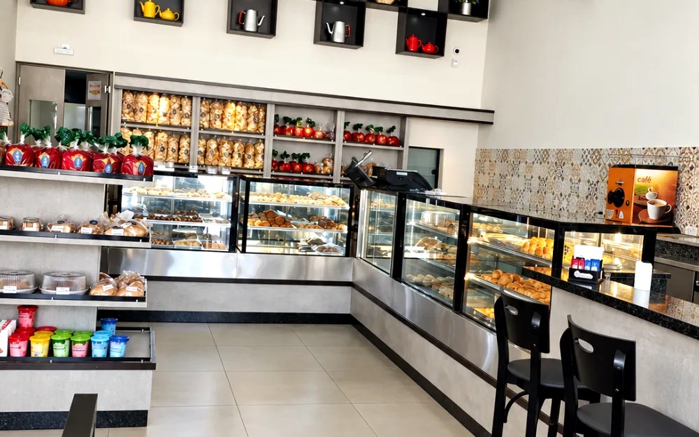 Balcão em L com vitrines, mesas altas e nichos decorativos, em área de atendimento