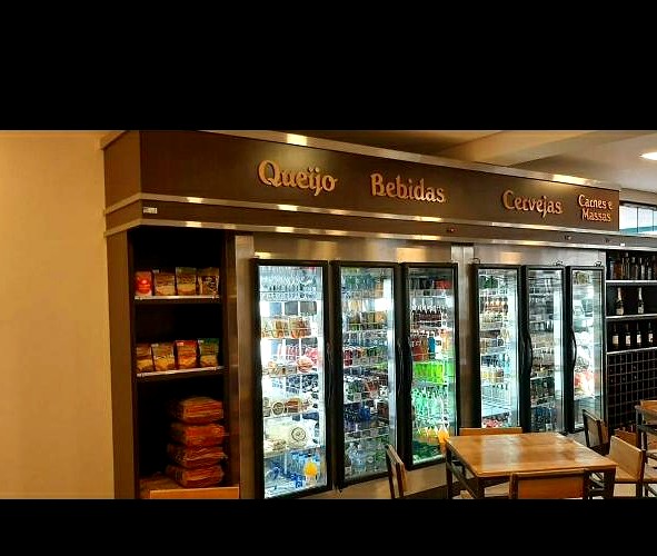 Walk-in cooler abastecido, com letreiro iluminado sobre as portas de vidro escuro, sanca iluminada em LED e prateleiras laterais