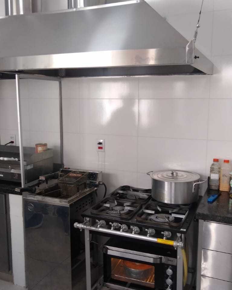 Cozinha industrial com fogão, coifa em aço inox e bancada de apoio