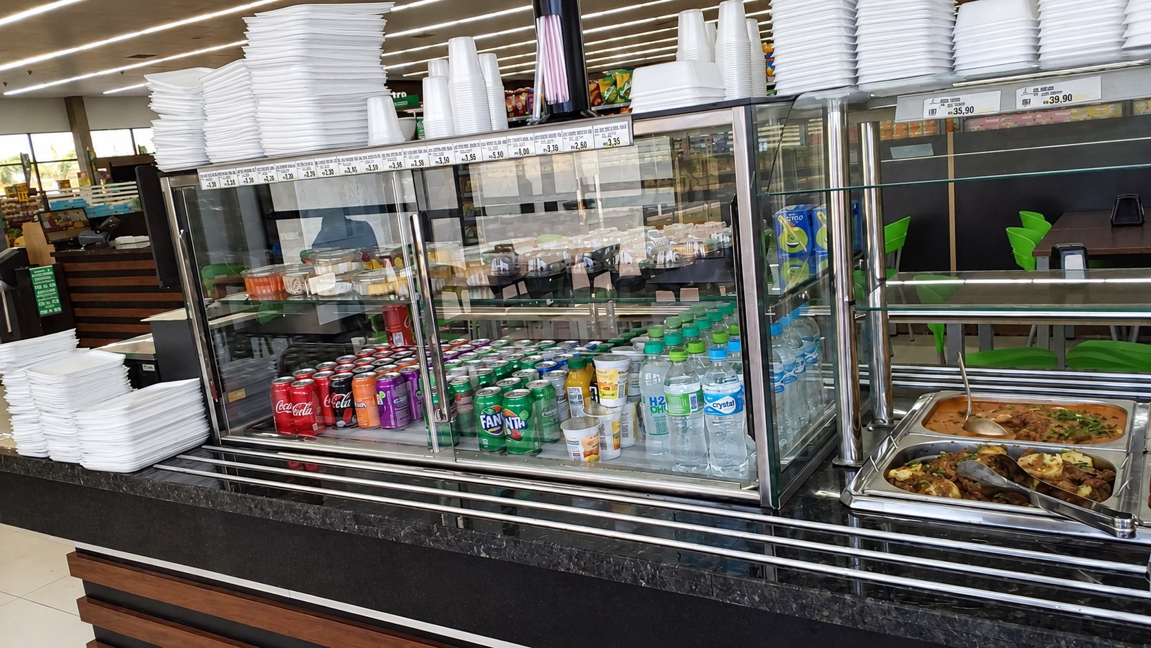 Pista de autosserviço em aço inox com cubas quentes e guichê de vidro, em restaurante