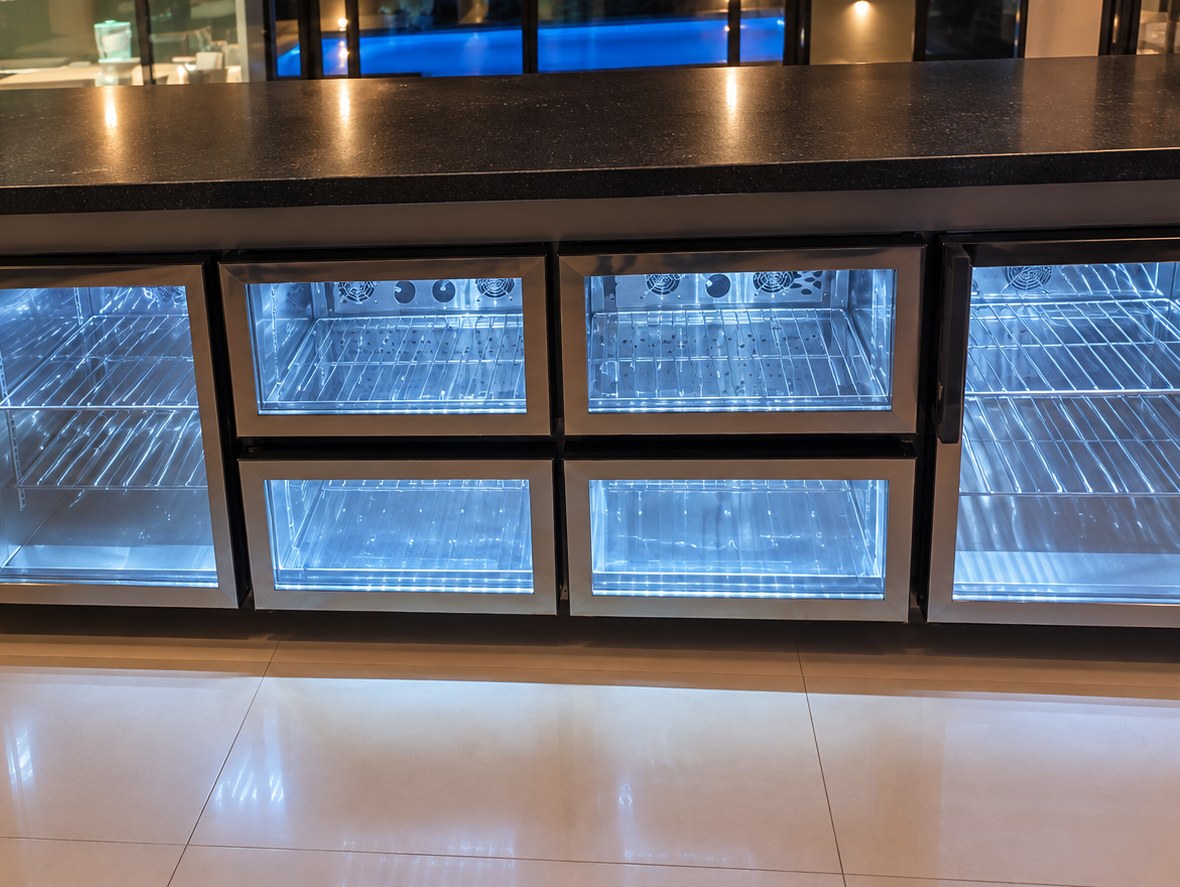 Balcão refrigerado de quatro portas de vidro com iluminação interna, em área de lazer com piscina