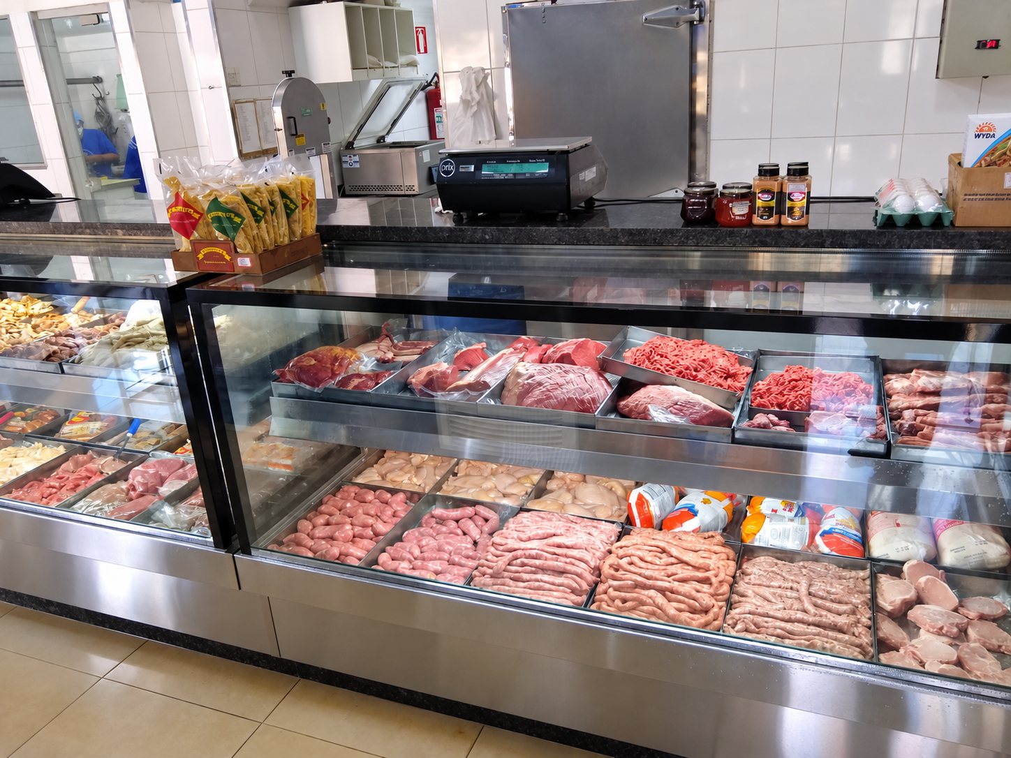 Vitrine expositora de açougue com carnes em bandejas, em aço inox e vidro reto