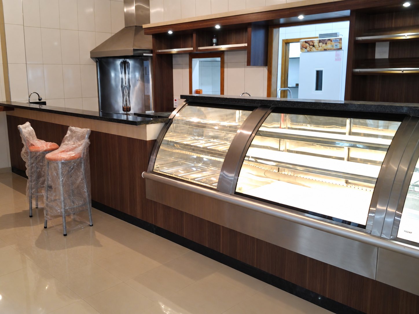 Vitrines de vidro curvo com iluminação interna, tampo de granito e base amadeirada, no balcão de atendimento