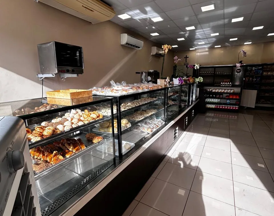 Balcão longo de pães e doces, com vitrines refrigeradas e forno de apoio