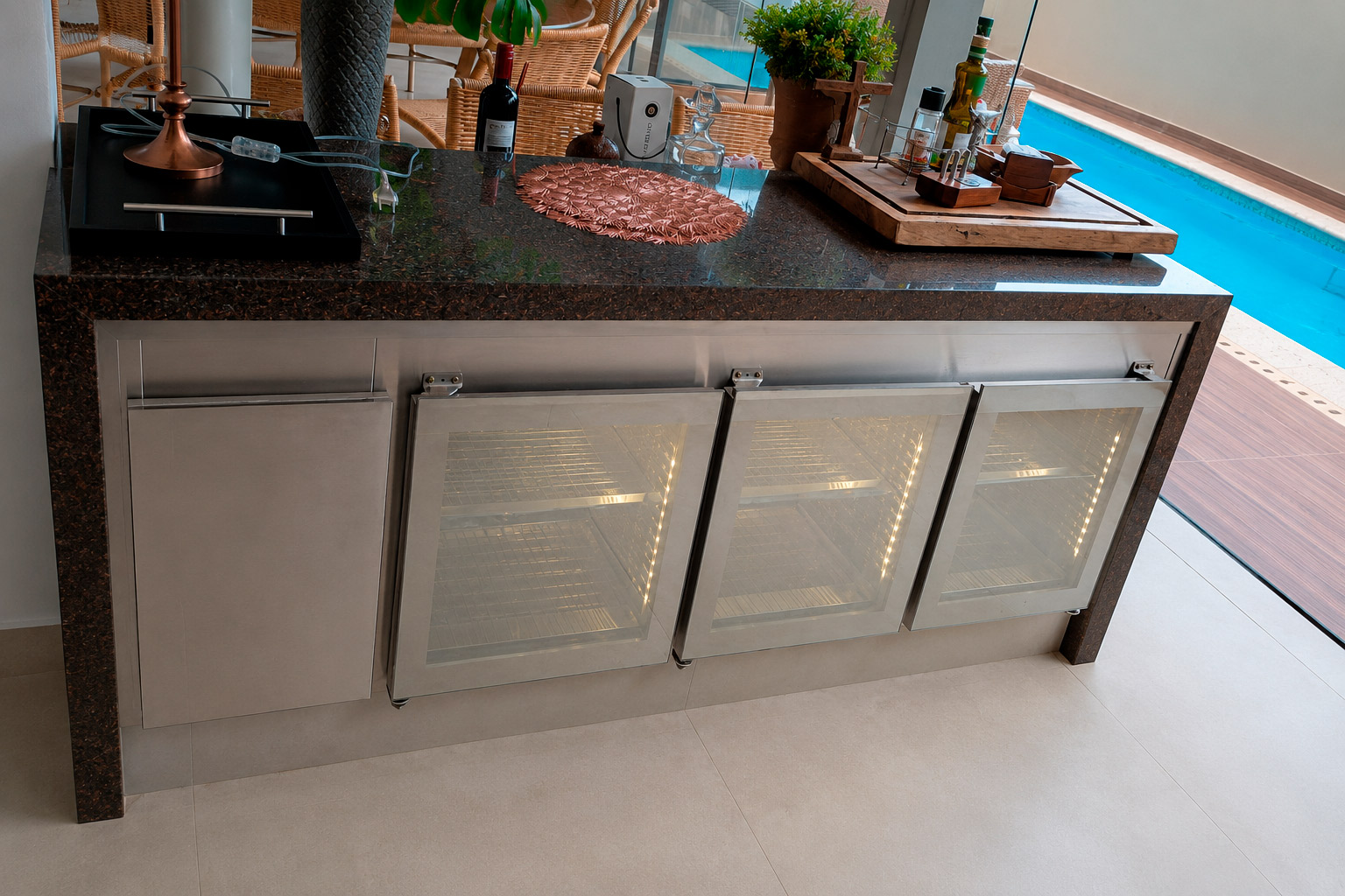 Balcão refrigerado em aço inox com portas de vidro instalado em área de lazer